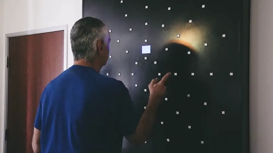 Man pressing a lit button on a dark DynaVision light board