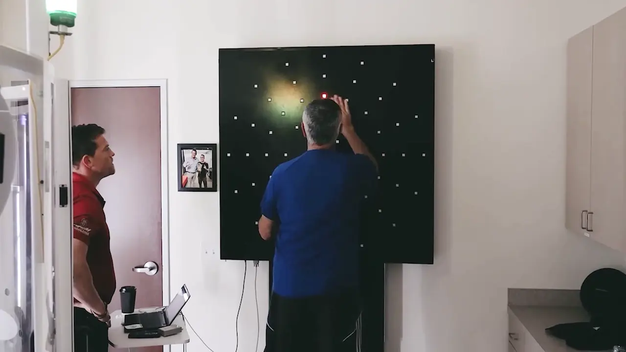 DynaVision attention training Adult patient reaching for a lit target on a DynaVision light board while a clinician watches