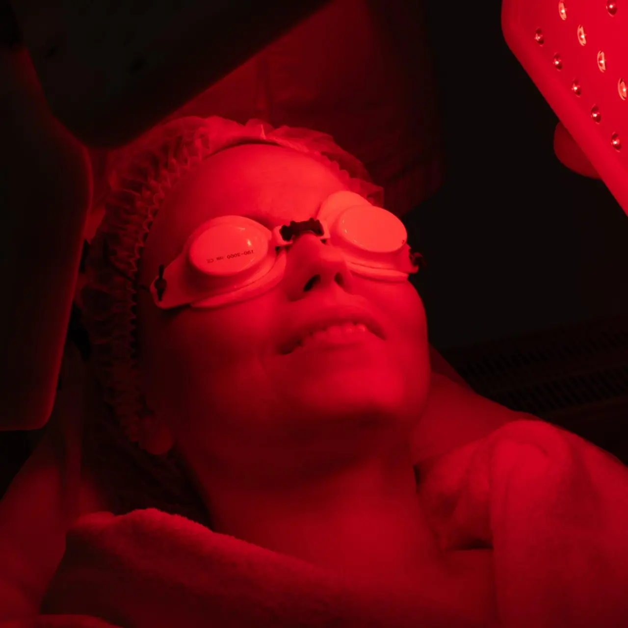 Light therapy session Patient wearing eye protection under the red glow of a light therapy panel